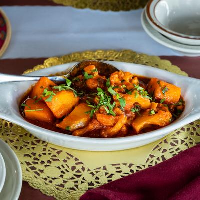 A white dish of Boneless chicken in curry sauce is placed on a golden doily.