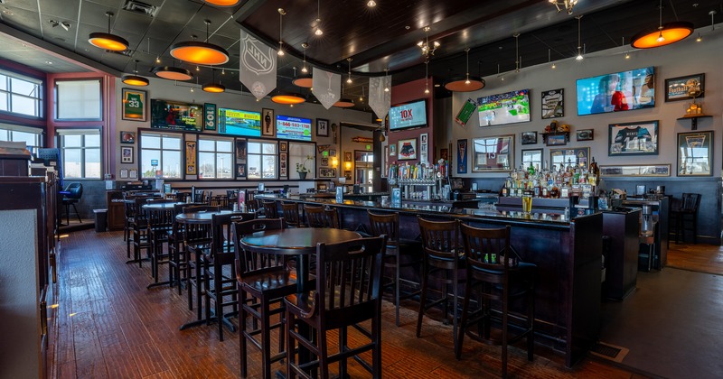 Interior of sports bar seating area with high tables and stools and bar