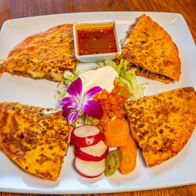 Birria quesadilla  served with sour cream salad, dipping sauce, and pickled veggies.