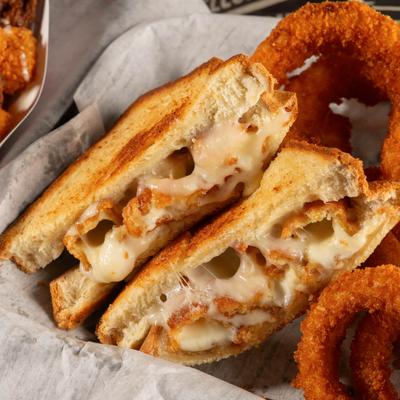 Grilled cheese sandwich with onion rings on the side.