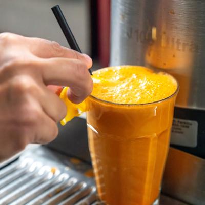 A hand garnishing a glass of fresh-squeezed juice with a slice of citrus.