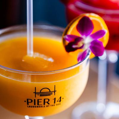 Frozen orange margarita,  garnished with an orange wheel and a purple flower, close up.