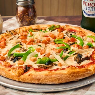 Veggie Pizza served with a bottle of beer and codiments.