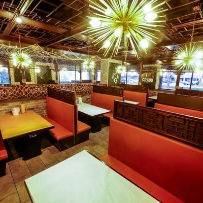 Restaurant interior with red booth seating and modern spiky chandeliers.