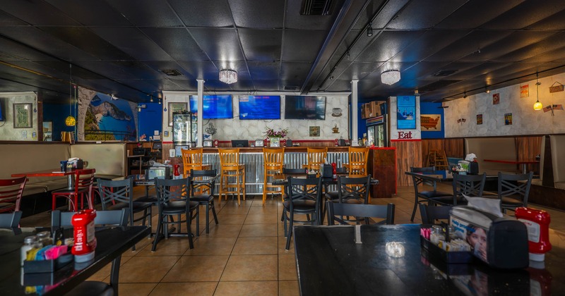 Interior, tables, wooden chairs, and a bar with screens