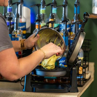 Staff memeber pouring a batter from a metal bowl into the waffle maker.