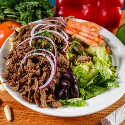 Beef shawarma bowl with rice, fresh salad, and hummus.