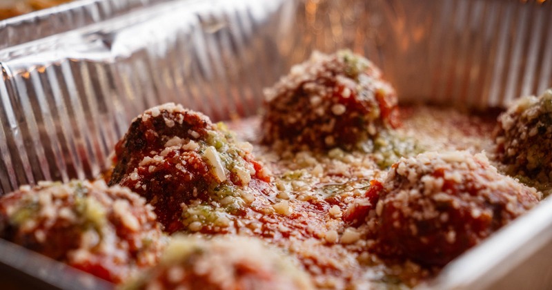 Meatballs, in red sauce, topped with basil pesto