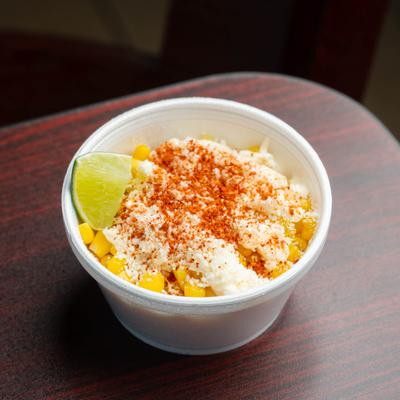 Mexican street corn in a cup with cotija cheese, chili powder, and lime.