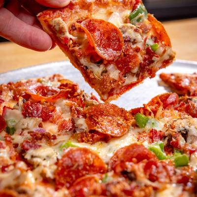 Hand lifting a square pepperoni pizza slice from the pie.