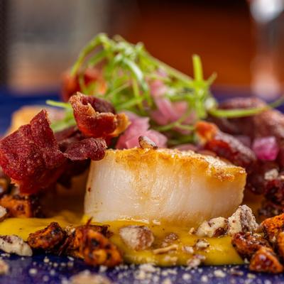 A close up view of scallop dish with corn puree, fennel, chili and fresh basil.