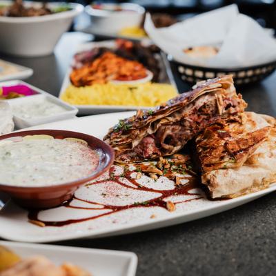 Palestinian chicken flatbread served with yoghurt, other dishes in the background.