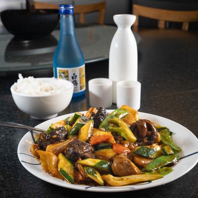 Stir-fried vegetables served with a side of rice and sake.