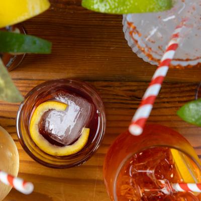 Overhead view of cocktails with citrus garnishes and striped straws.