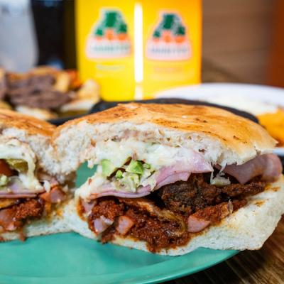 Marinated pork sandwiches with lettuce, tomato, cheese, onions, and avocado.