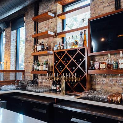 Area behind a bar, hard liquor bottles, glassware, draft beer