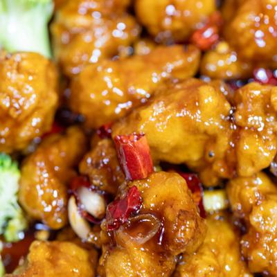Close-up of spicy glazed chicken with dried red chilies.