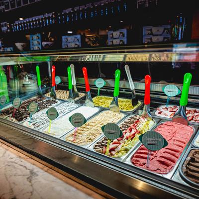 Variety of colorful gelato flavors in a display case with labels.