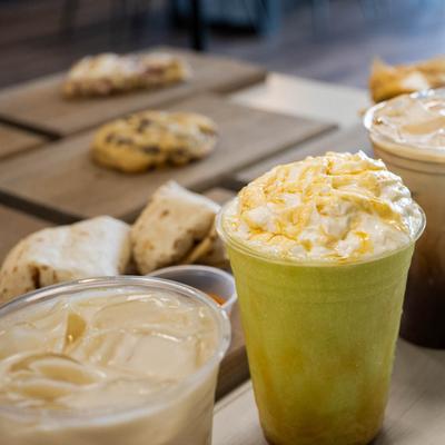 Close-up of iced drinks on a table with blurred pastries in the background.