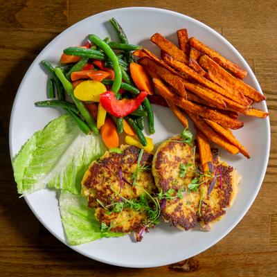 Crab cakes served with sweet potato fries and sauteed vegetables.