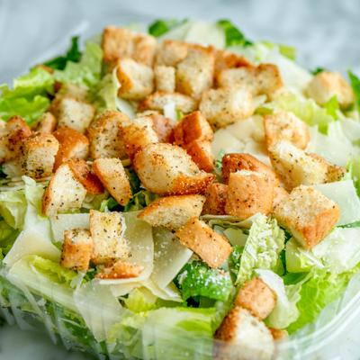 Caesar salad topped with croutons and shaved cheese.
