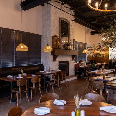 Interior, part of dining area with banquette and a fireplace, tables set with  tableware.
