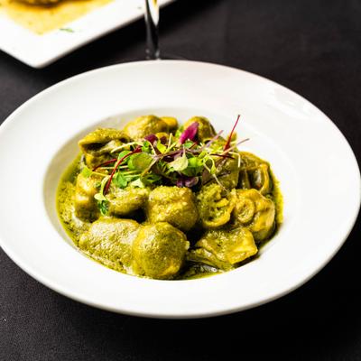Money bag pasta in pesto sauce garnished with microgreens.