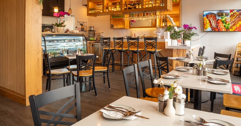 Interior of a restaurant with set tables, a bar area
