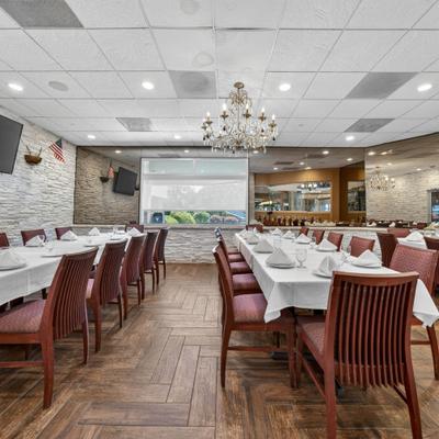 Interior featuring table seating, wood-look flooring, stacked stone walls and a chandelier.