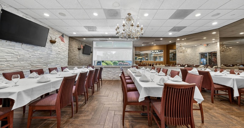 Dining room featuring white-clothed tables, wooden chairs, and a chandelier