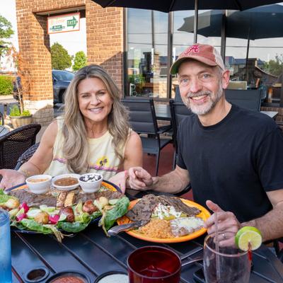 Couple enjoying a large meal at a restaurant outdoor table.