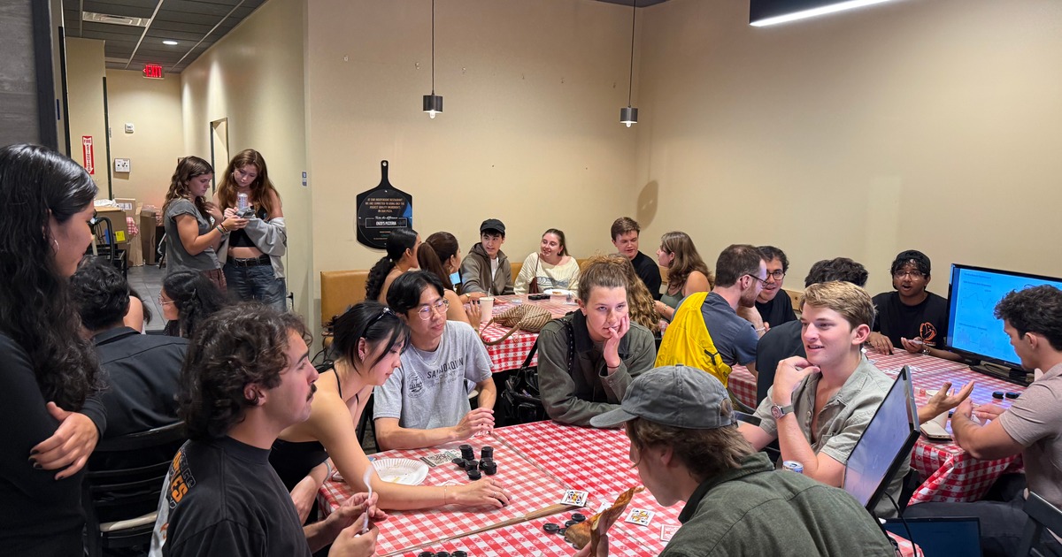 Group of people gathered around tables covered with checkered tablecloths