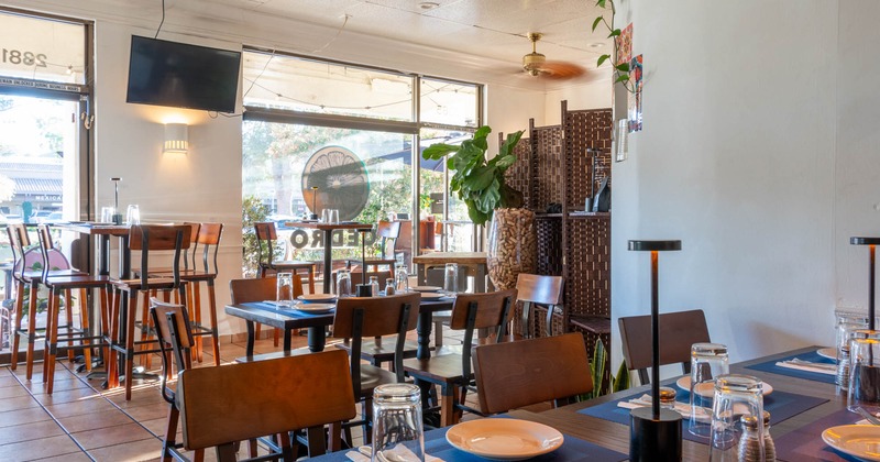 Interior, wide view of dining area, tables and chairs, TV screen on the wall