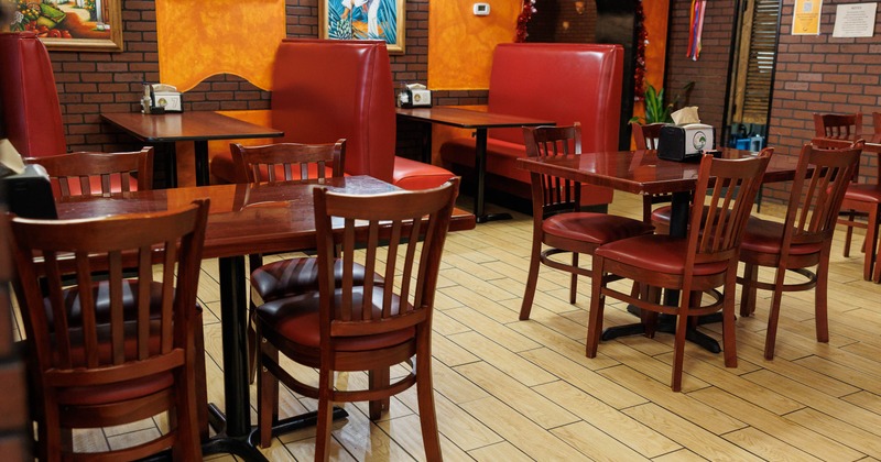 Interior of a restaurant with red booths, wooden furniture and colorful decor