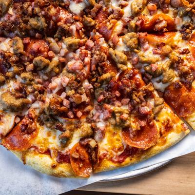 The Beast Pizza with pepperoni, sausage, bacon and ham, close-up.