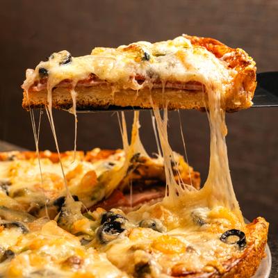 A slice being lifted from a thick-crust pizza with melted, stretchy mozzarella cheese.