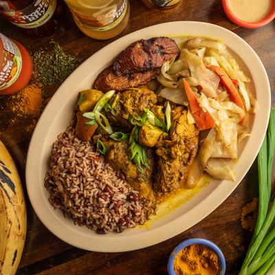 Curry chicken served with sides of rice and peas and cabbage, top view.