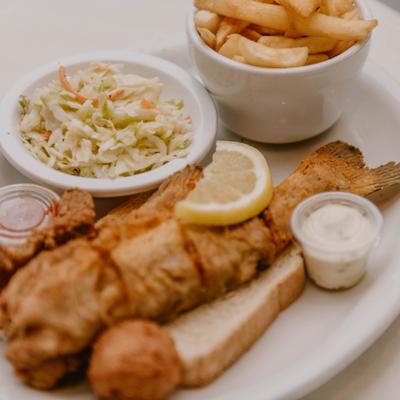 Fried catfish served alongside fries, coleslaw and dipping sauces.