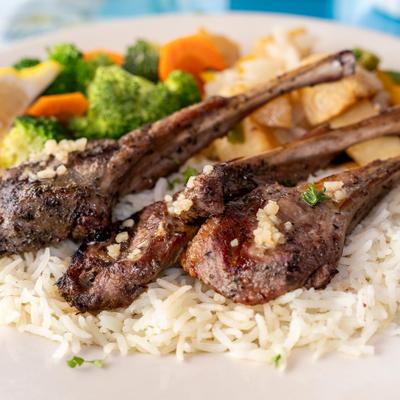 Lamb chops served with white rice and steamed vegetables.