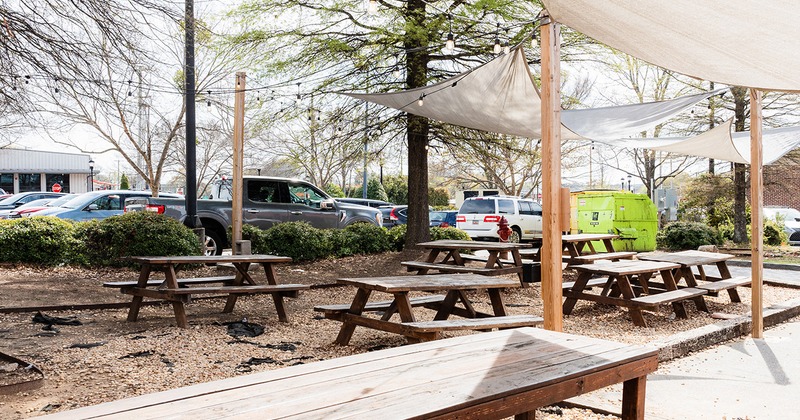 Outdoor seating area, wooden tables with benches and sun shades