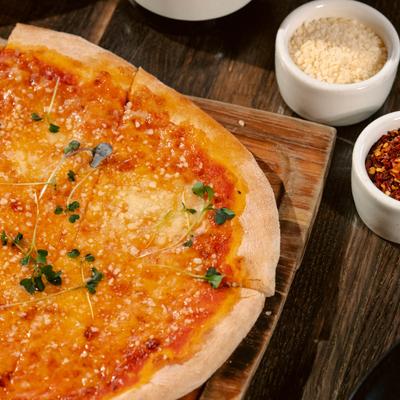 Four cheese pizza served on a wooden table with condiments.