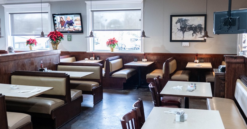 Interior of a restaurant with booths and tables, dark wood paneling, and a television on the wall