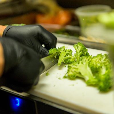 Food preparation, chopping broccoli on a kitchen table, close up.