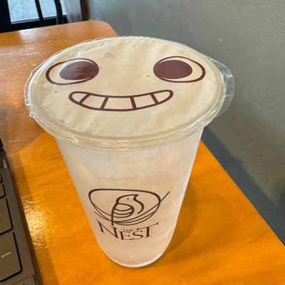 Iced beverage in a plastic cup with a smiling face lid.