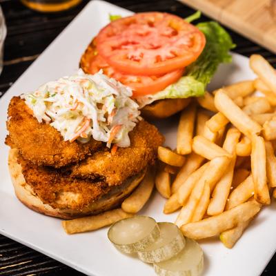 Firecracker sandwich with coleslaw, lettuce, tometoes and a side of fries.
