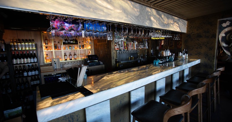 Interior, bar area, marble top bar with wooden bar stools, drink shelves behind the bar