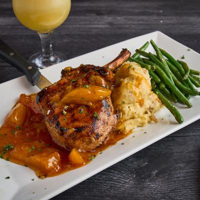 Peach Moonshine Glazed Porkchop, served with mashed potatoes and green beans.