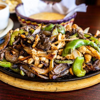 Mixed Fajitas served in a skillet on a wooden base.