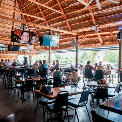 People dining in an open-air tiki bar restaurant.