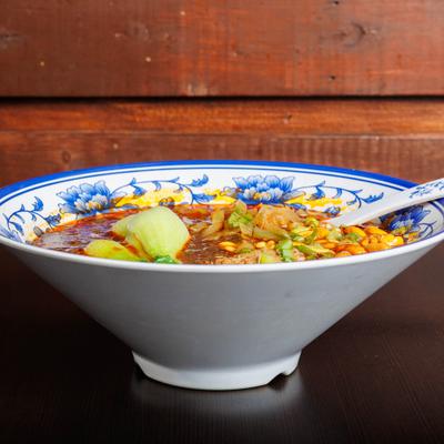 Spicy red noodle soup with bok choy, scallions, and peanuts.